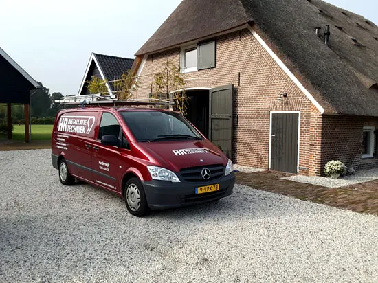 Rode bus van HR Installatie Techniek voor een woning met rieten dak