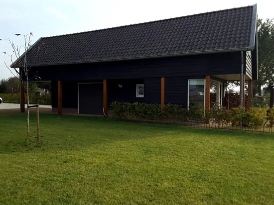Zwarte houten woning met overkapping en grasveld